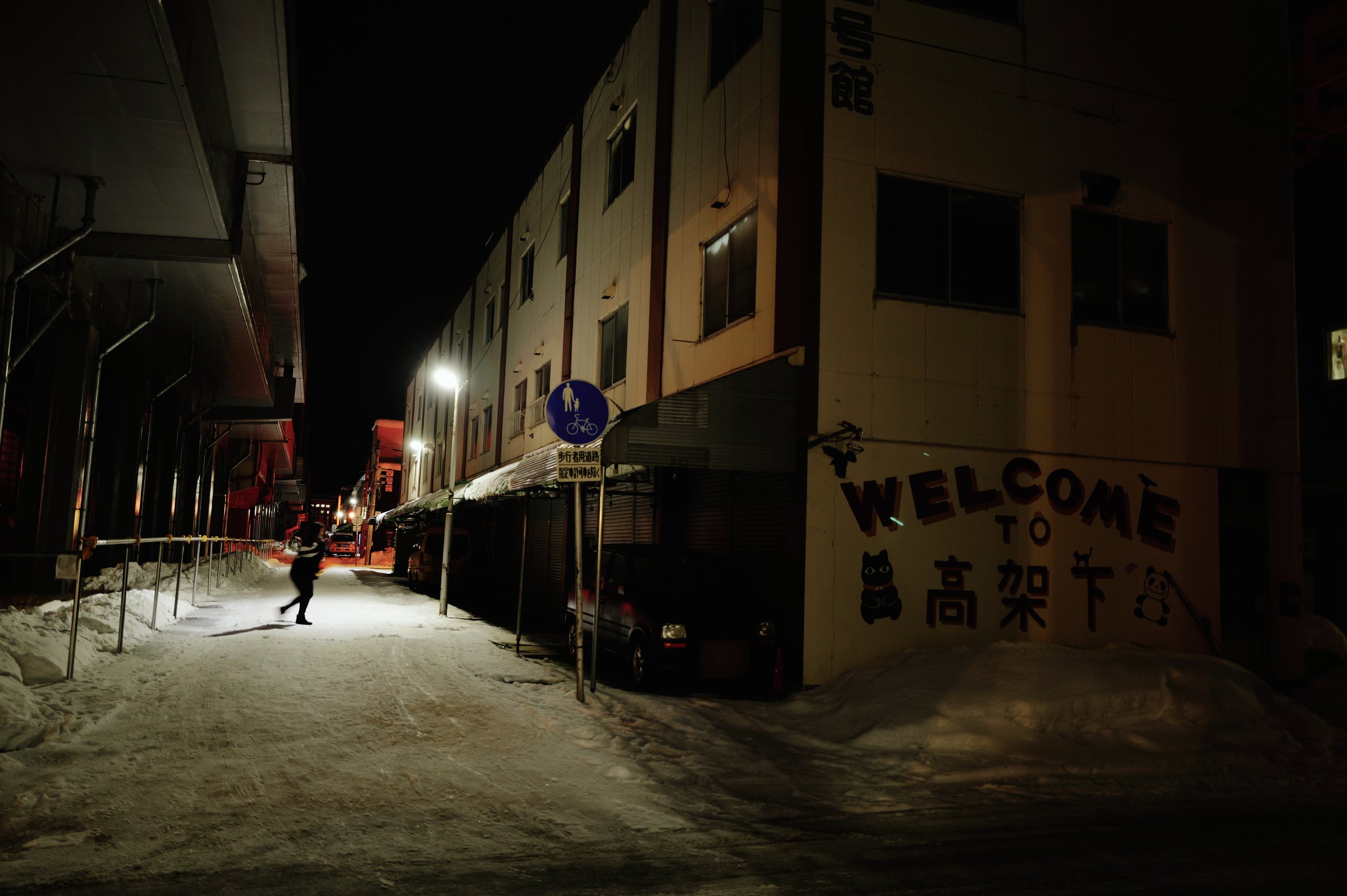 雪の夜の通りと、壁に描かれた「WELCOME」の文字