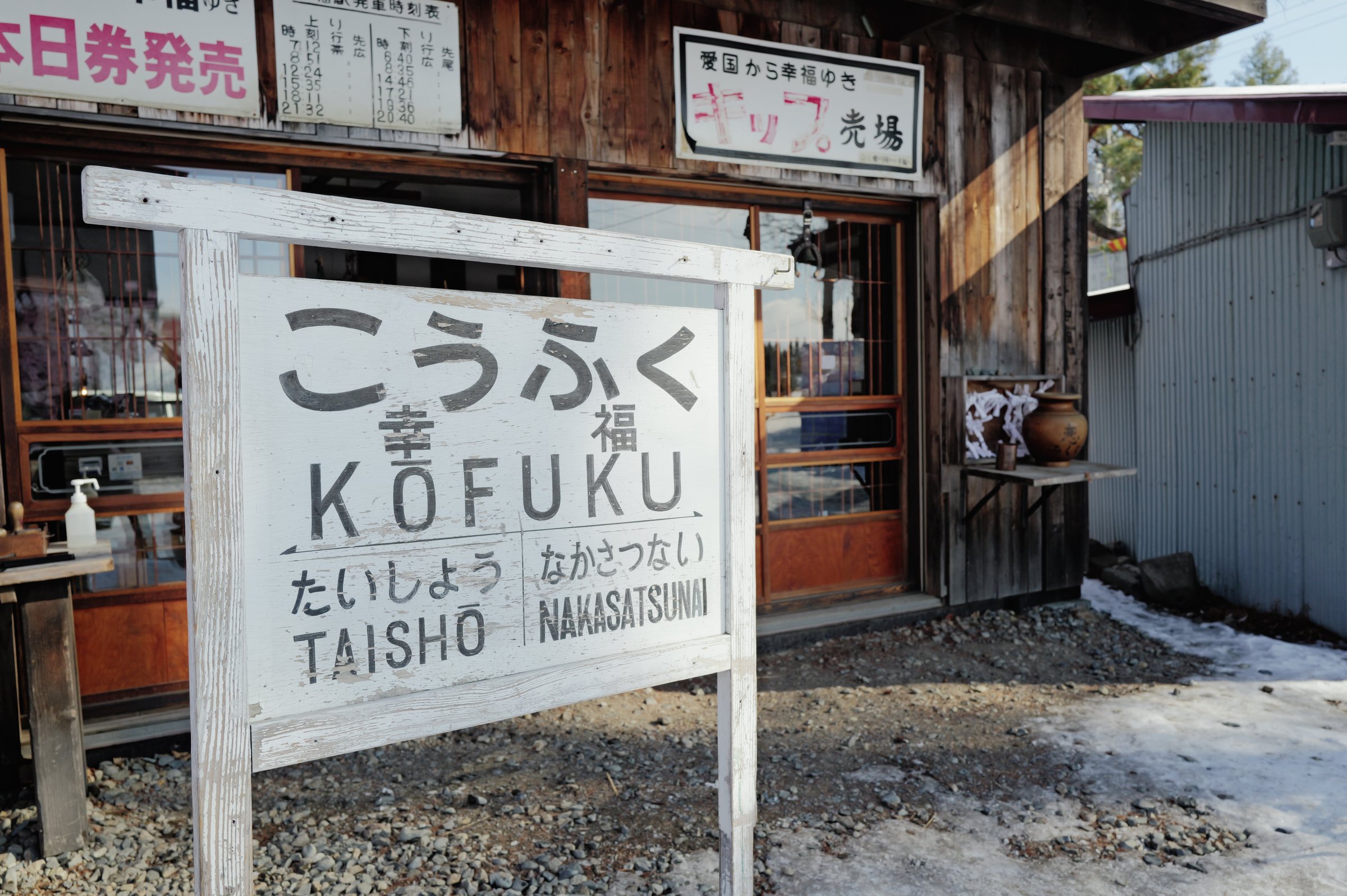 売店の前の「こうふく KOFUKU」の駅名標