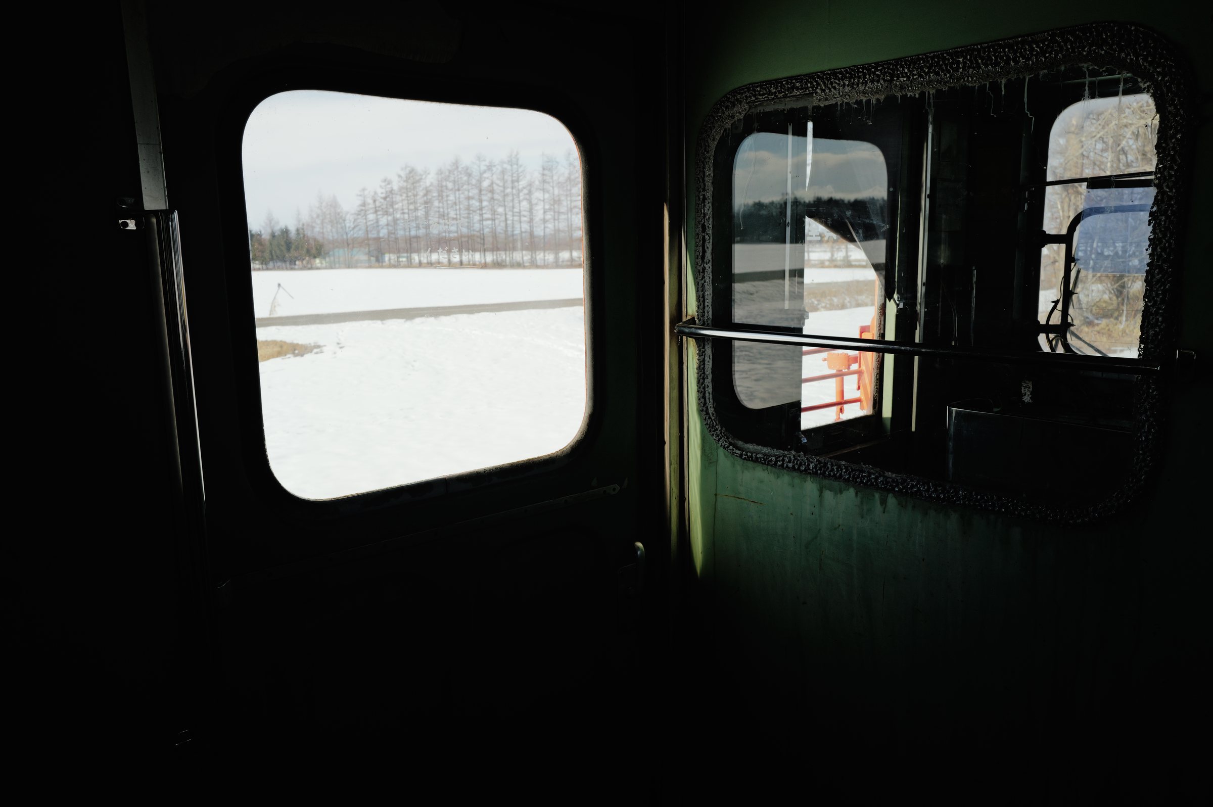 暗い車内の窓に切り取られた、雪の景色