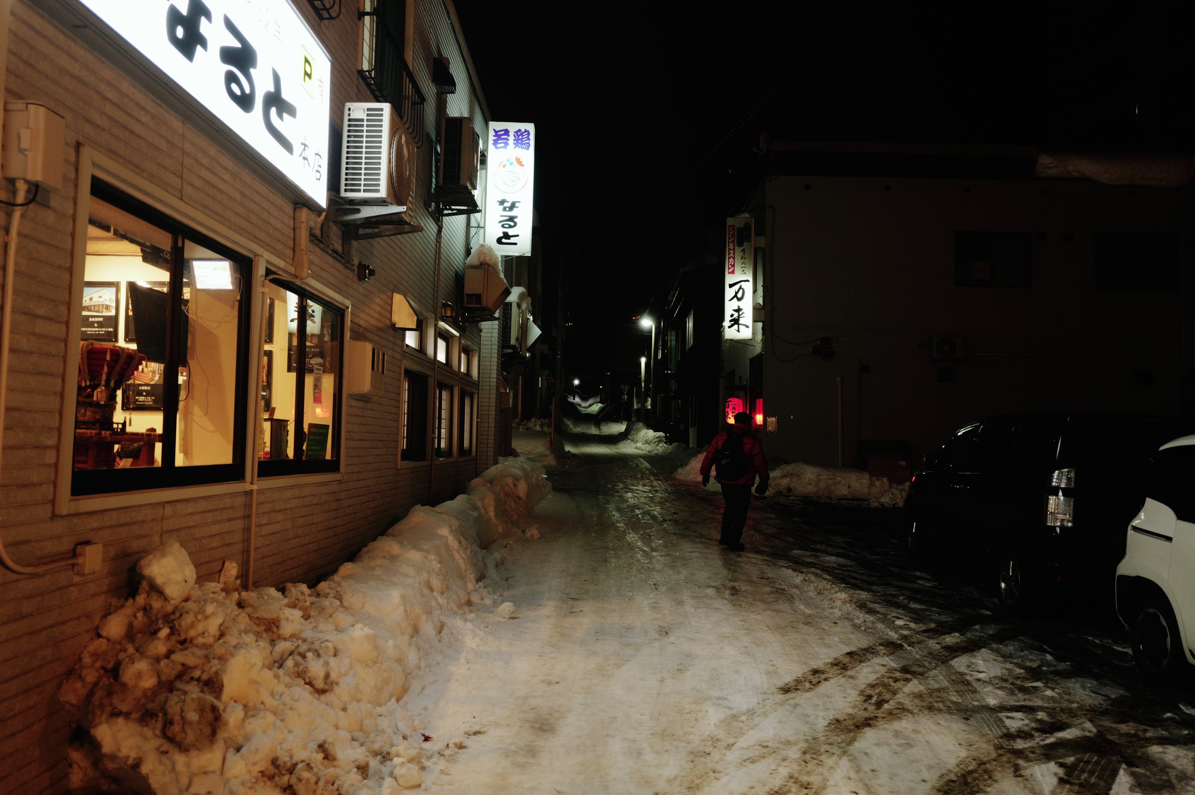 灯りのもれる店の脇の、雪に覆われた暗い通り
