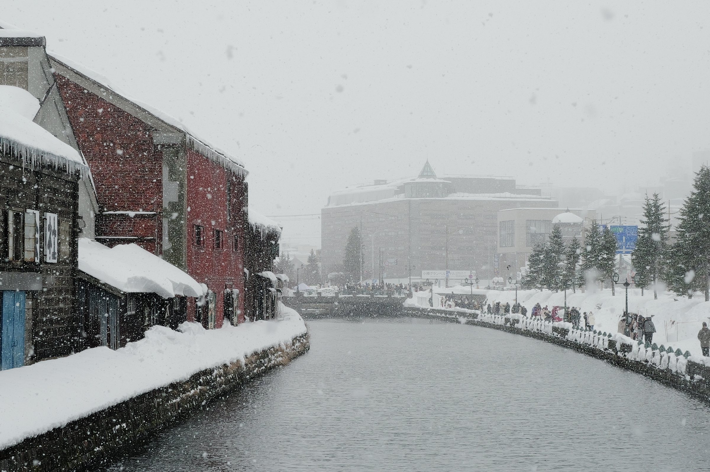 雪の岸に沿って続く運河と、その先の建物