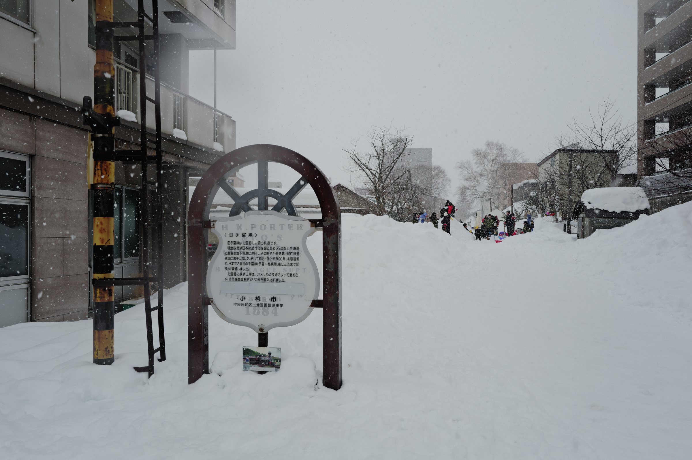 雪に埋もれた線路跡に立つ、旧手宮線の説明板