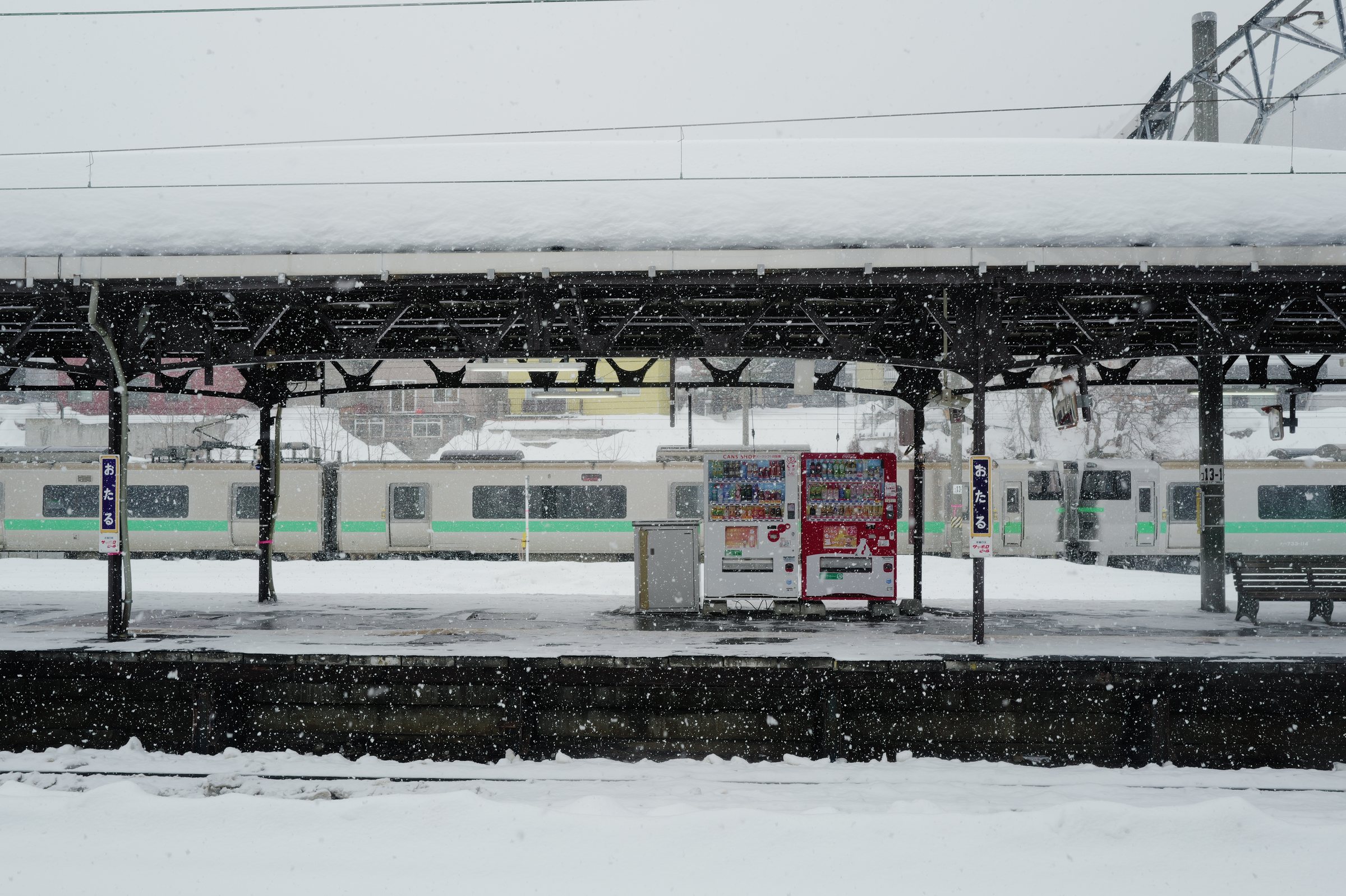 雪の降るホームと、屋根の下に止まる列車