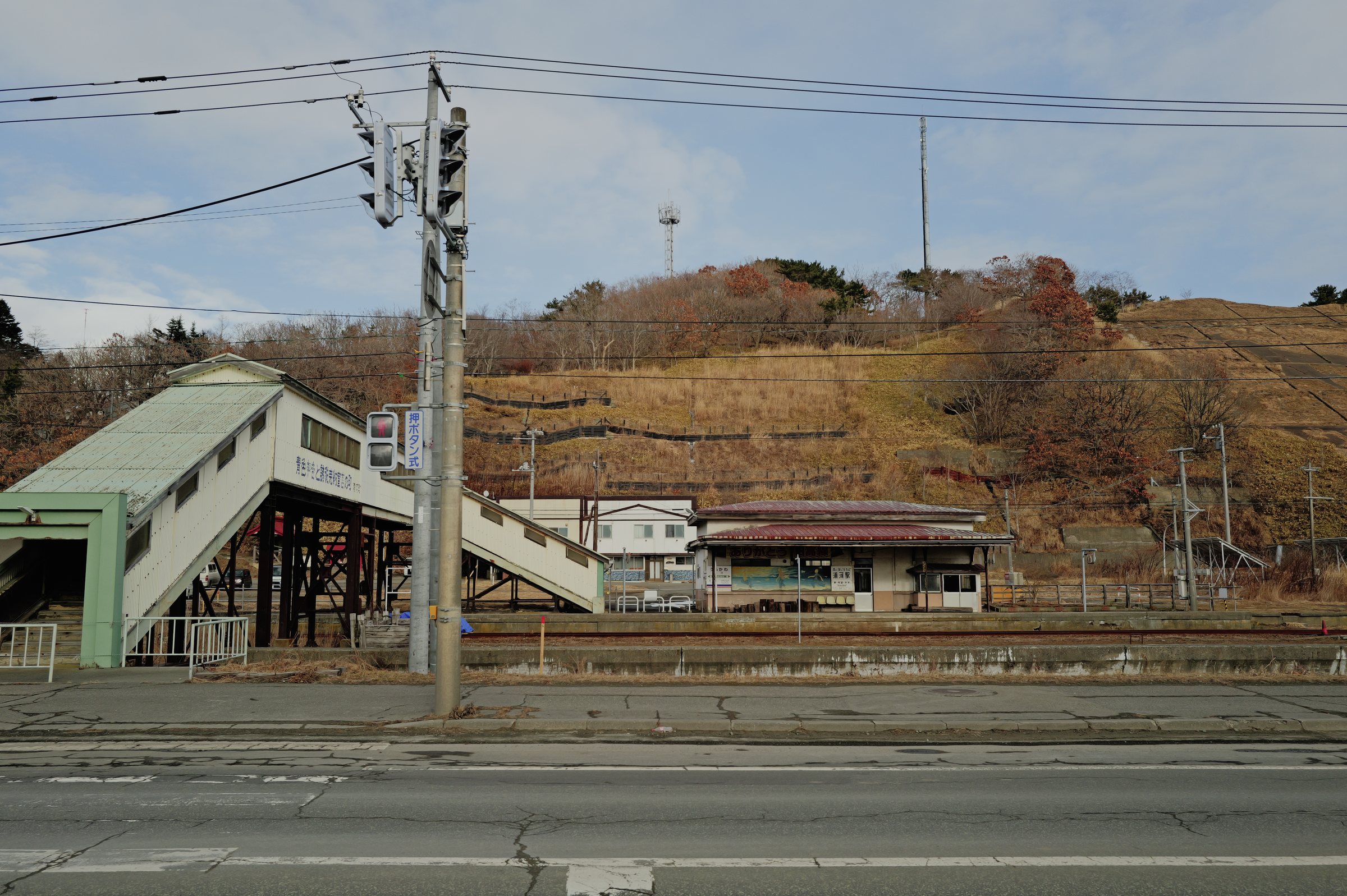 道路の向こうに見える、駅の跨線橋と駅舎