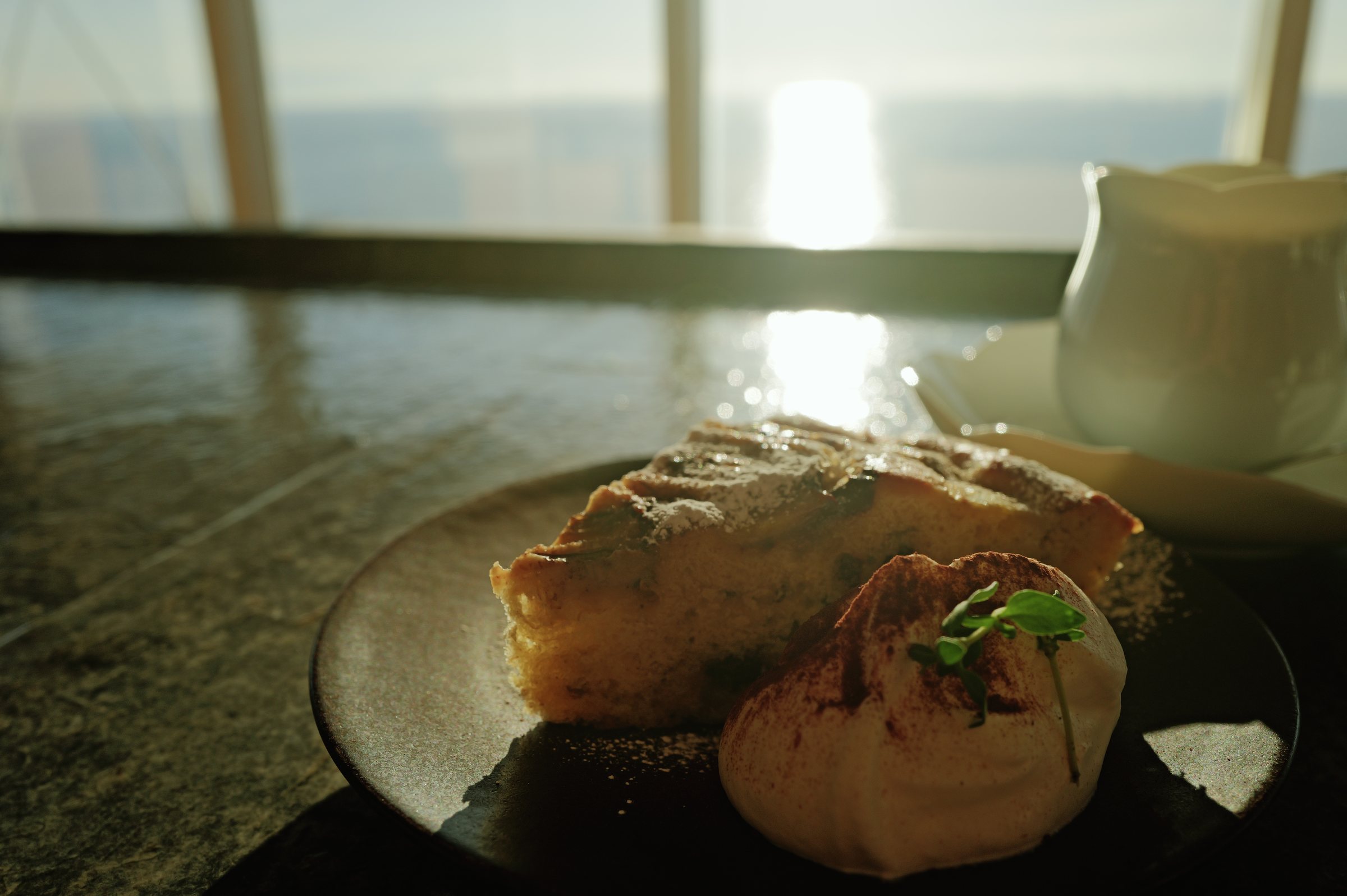 光る海を背にした皿のケーキ
