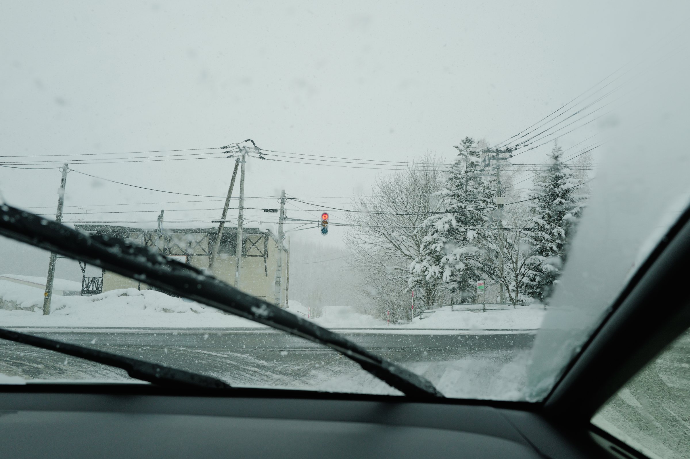 吹雪の中、ワイパーの動くフロントガラスと交差点