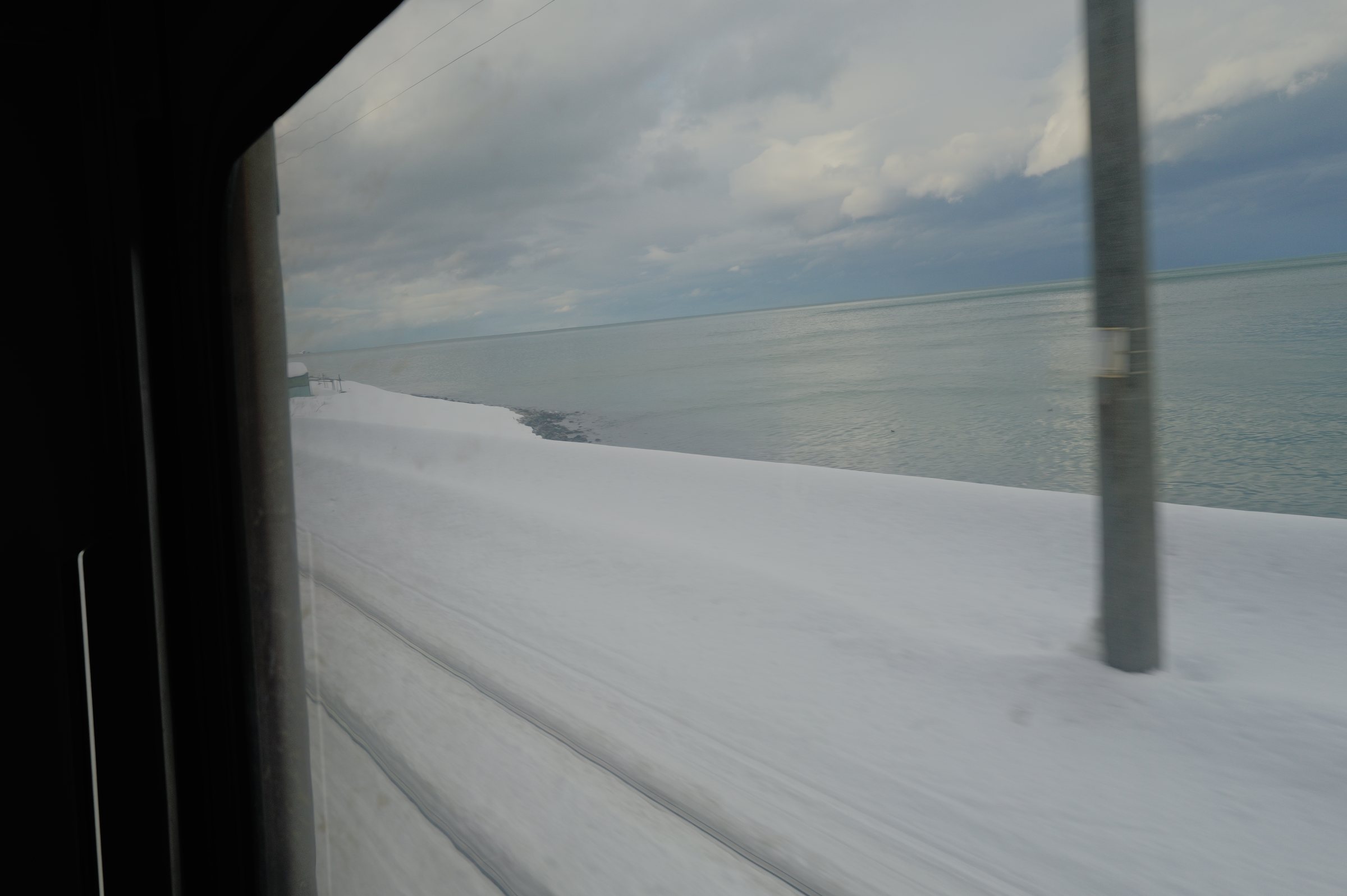 流れていく雪の浜と、その向こうの海