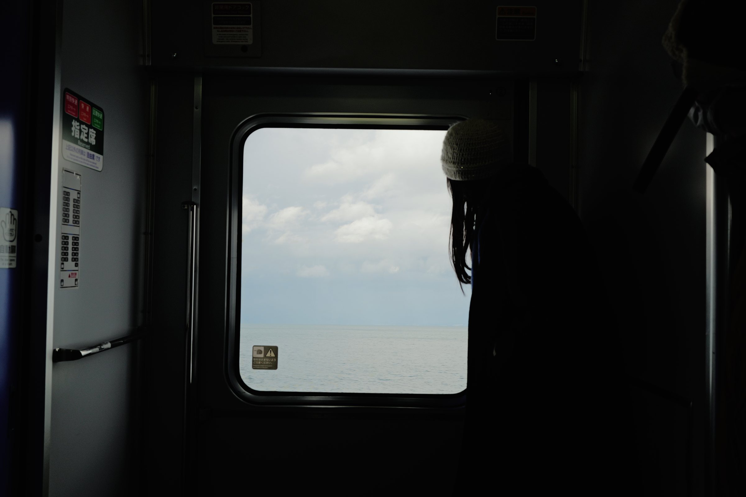 ドアの窓の向こうの海を眺める人の影