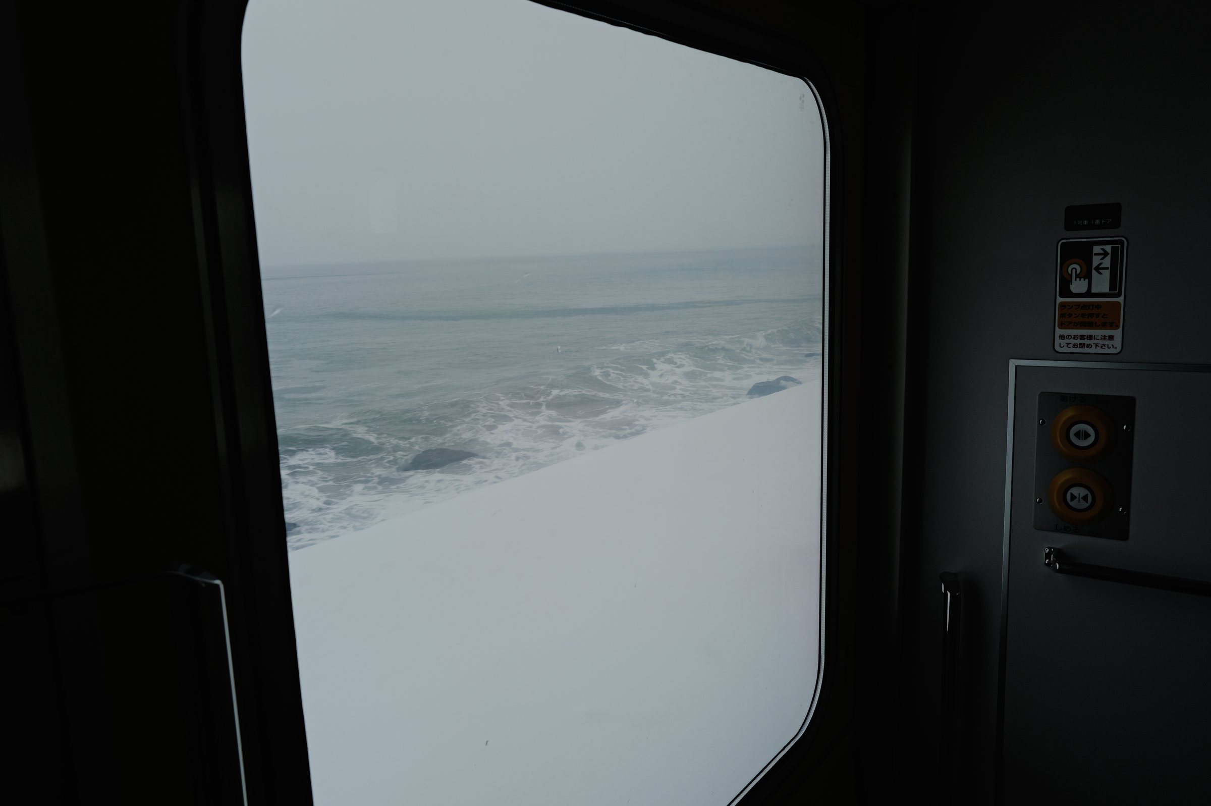 窓の向こうの雪の斜面と、荒れた海