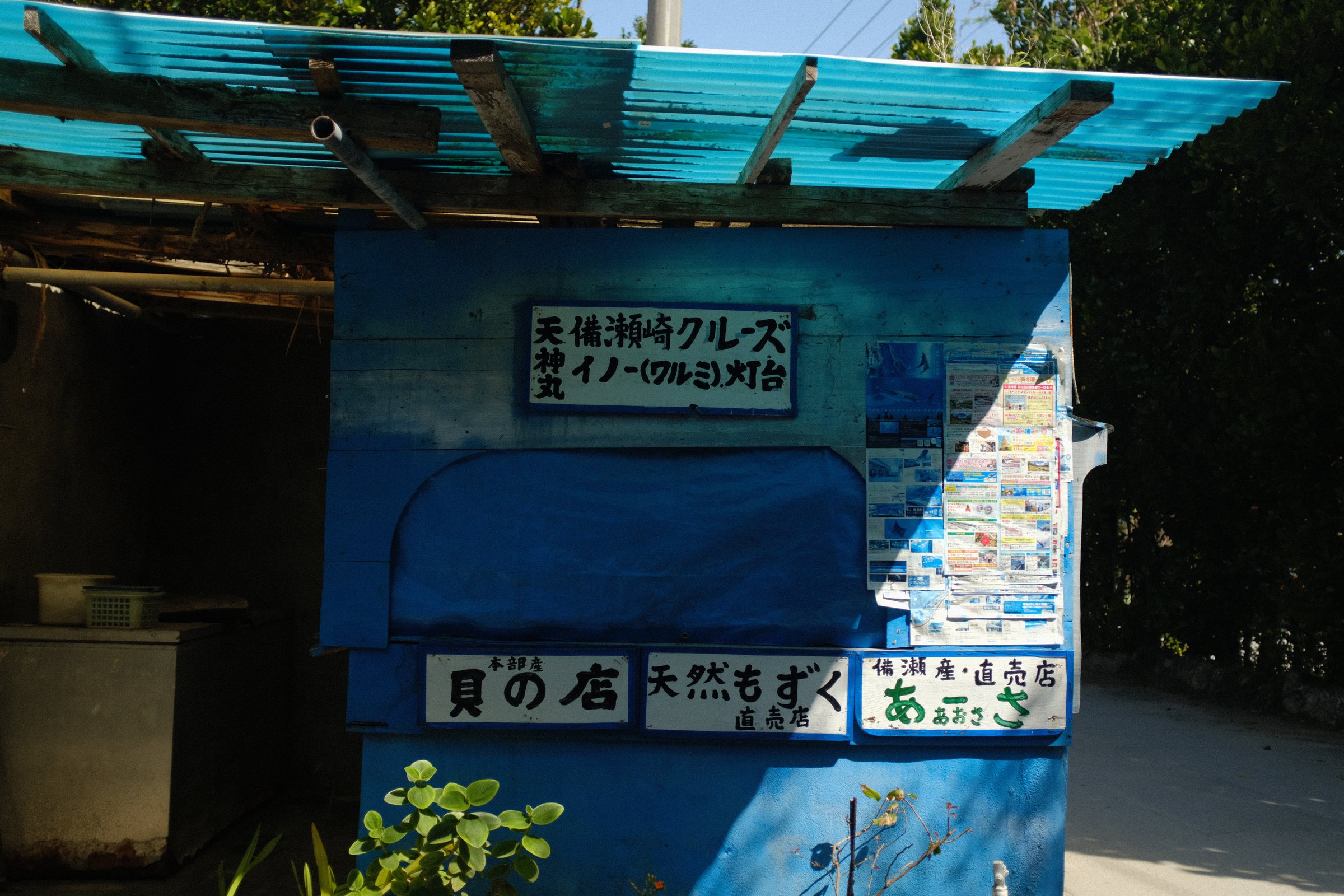 トタン屋根の青い小屋の店と、手書きの看板