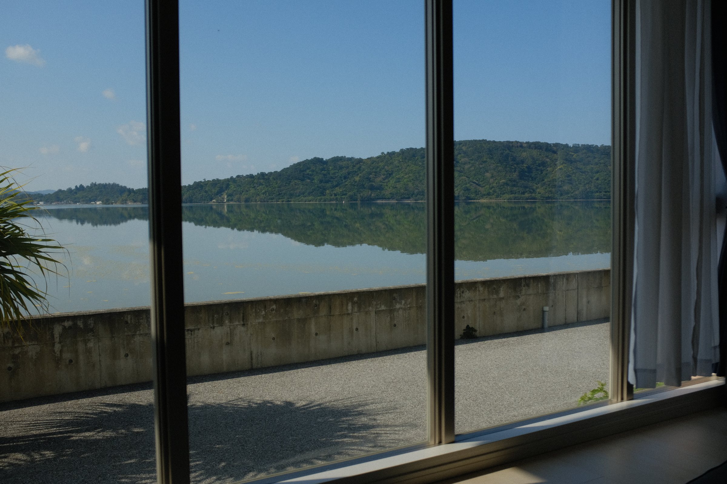 大きな窓の向こうで、対岸の山を鏡のように映す内海