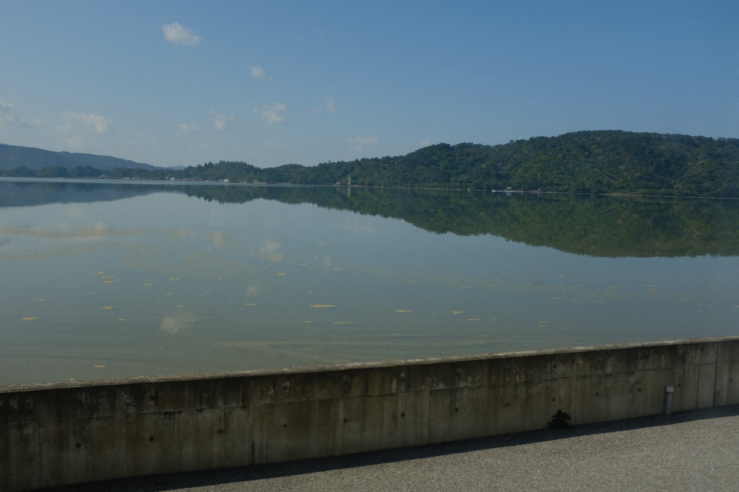波のない水面に映る、対岸の山と雲