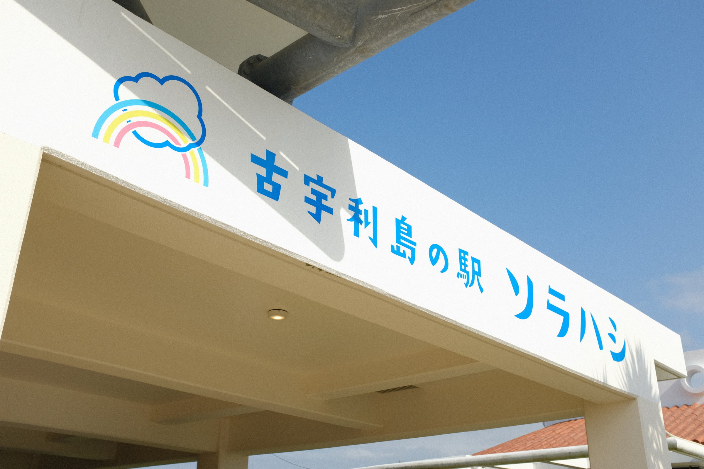虹の絵と「古宇利島の駅 ソラハシ」の文字が書かれた屋根