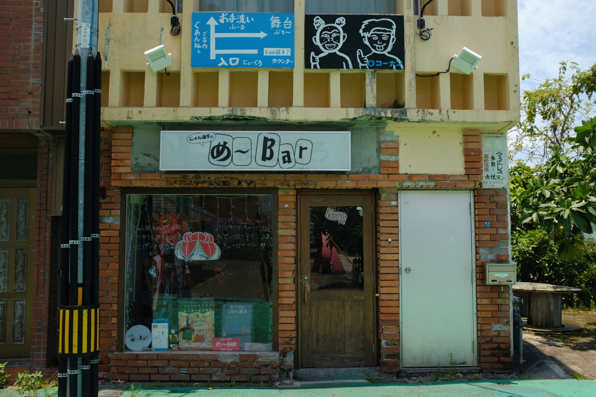 レンガの壁に看板の並ぶ、小さなバーの店先