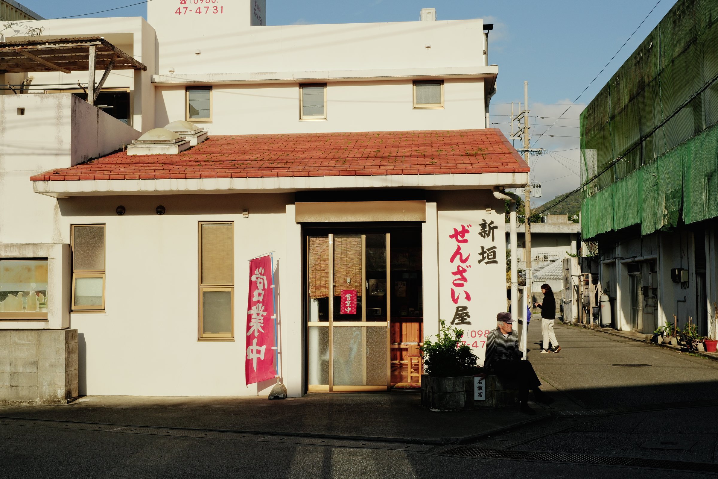 夕方の光を受ける、赤い瓦屋根の小さなぜんざい屋