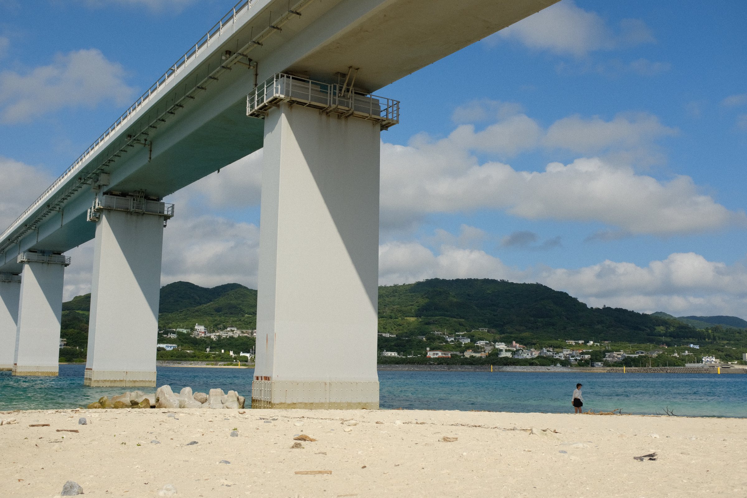海の上をまたぐ大きな橋と、その下の白い砂浜