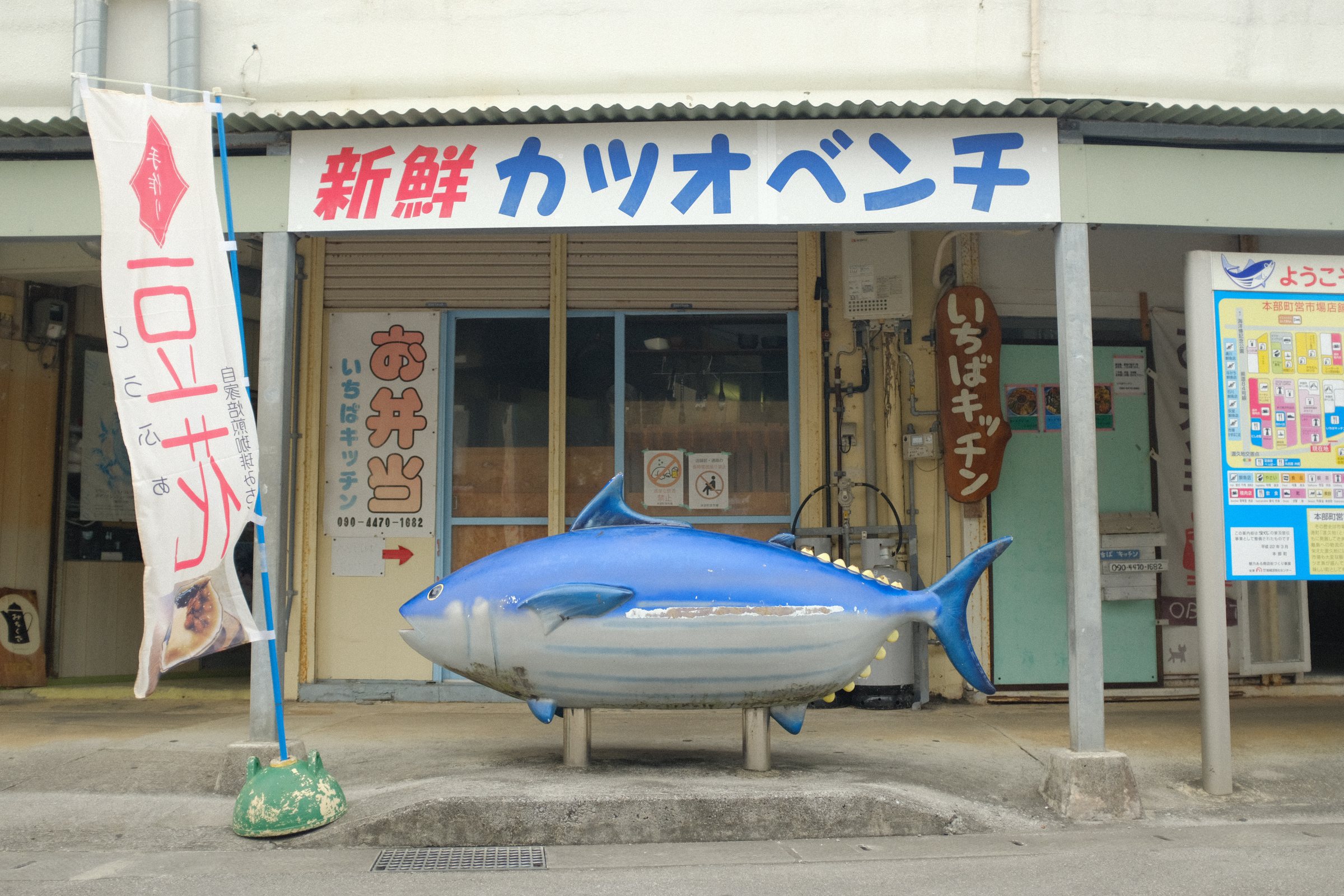 「新鮮カツオベンチ」の看板の下に置かれた、カツオの形のベンチ