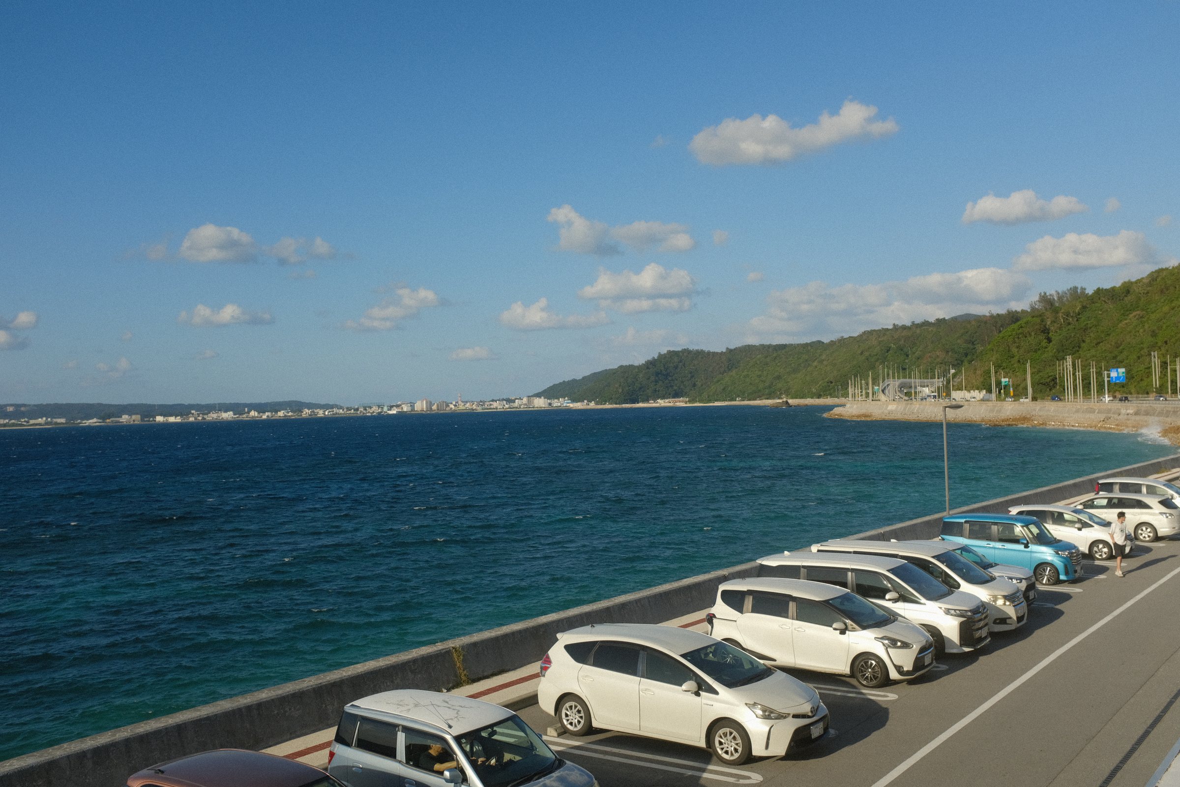 海沿いの駐車場と、その向こうに続く青い海と海岸線