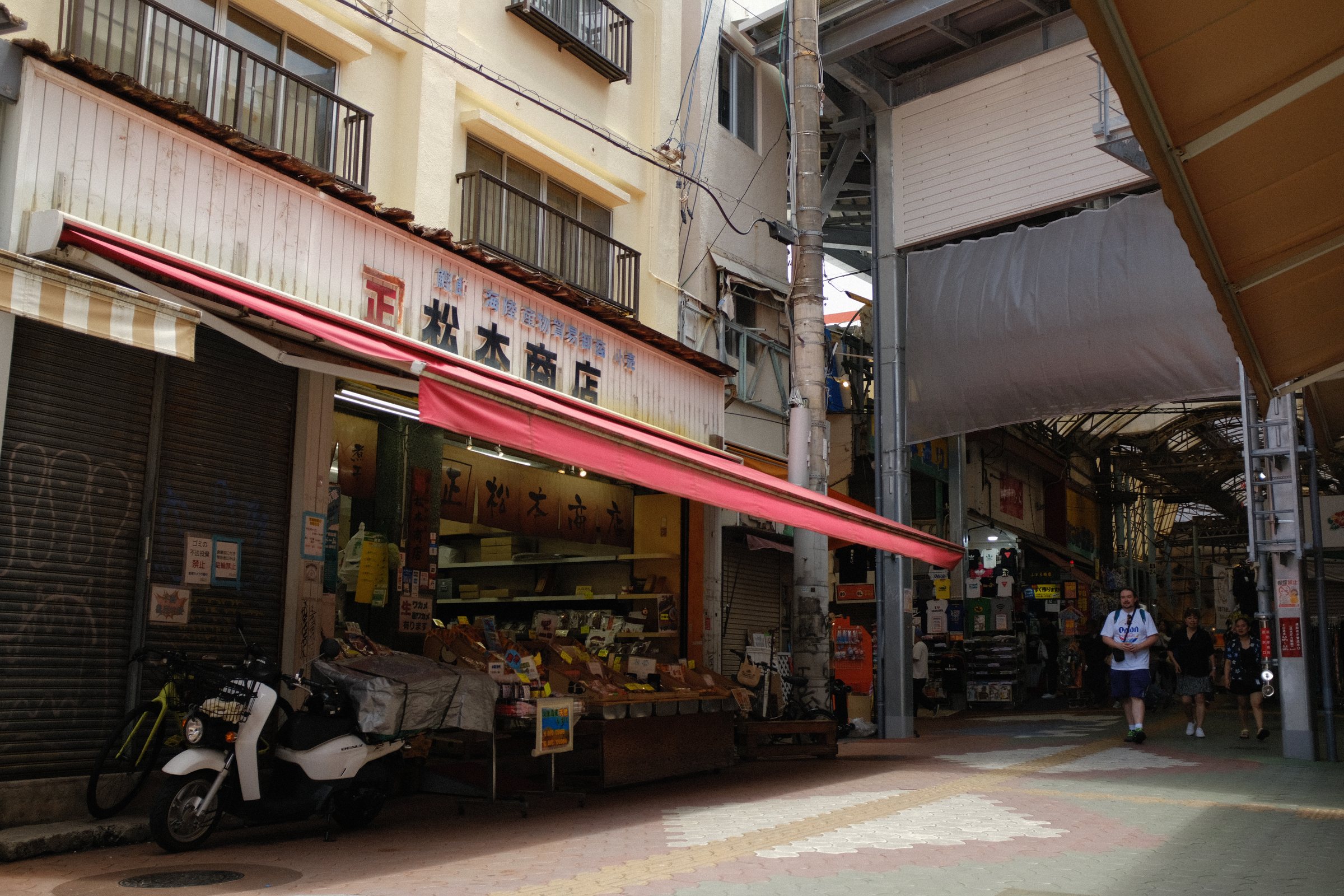 赤い日除けの商店の店先と、止められたスクーター