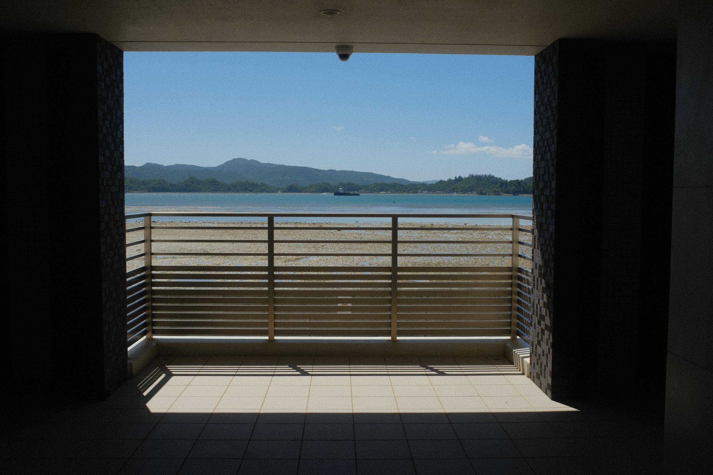 部屋の四角い開口の向こうの手すりと、内海