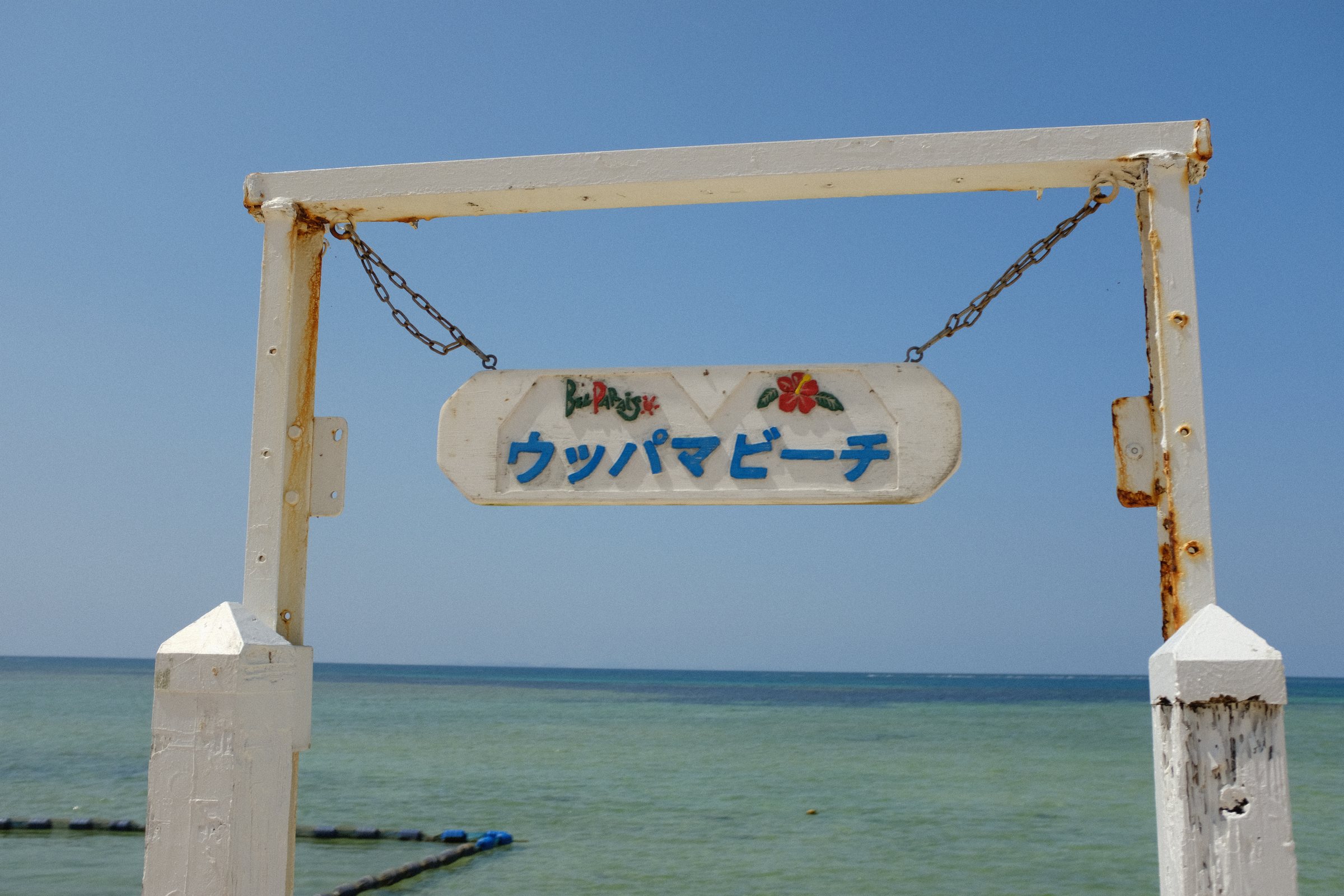 海を背にした門に掛かる「ウッパマビーチ」の看板