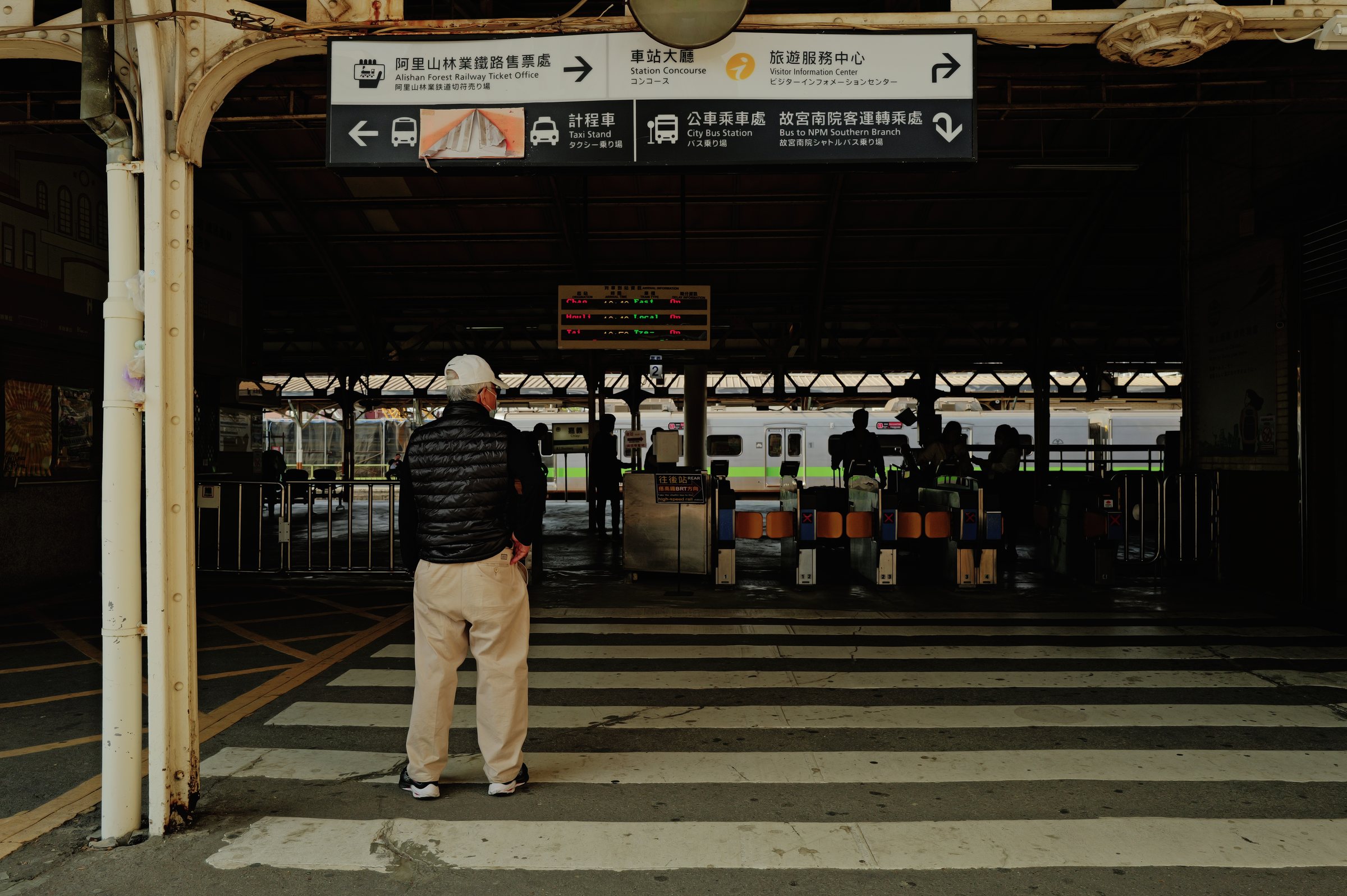 改札の手前で、ホームのほうを向いて立つ人の後ろ姿