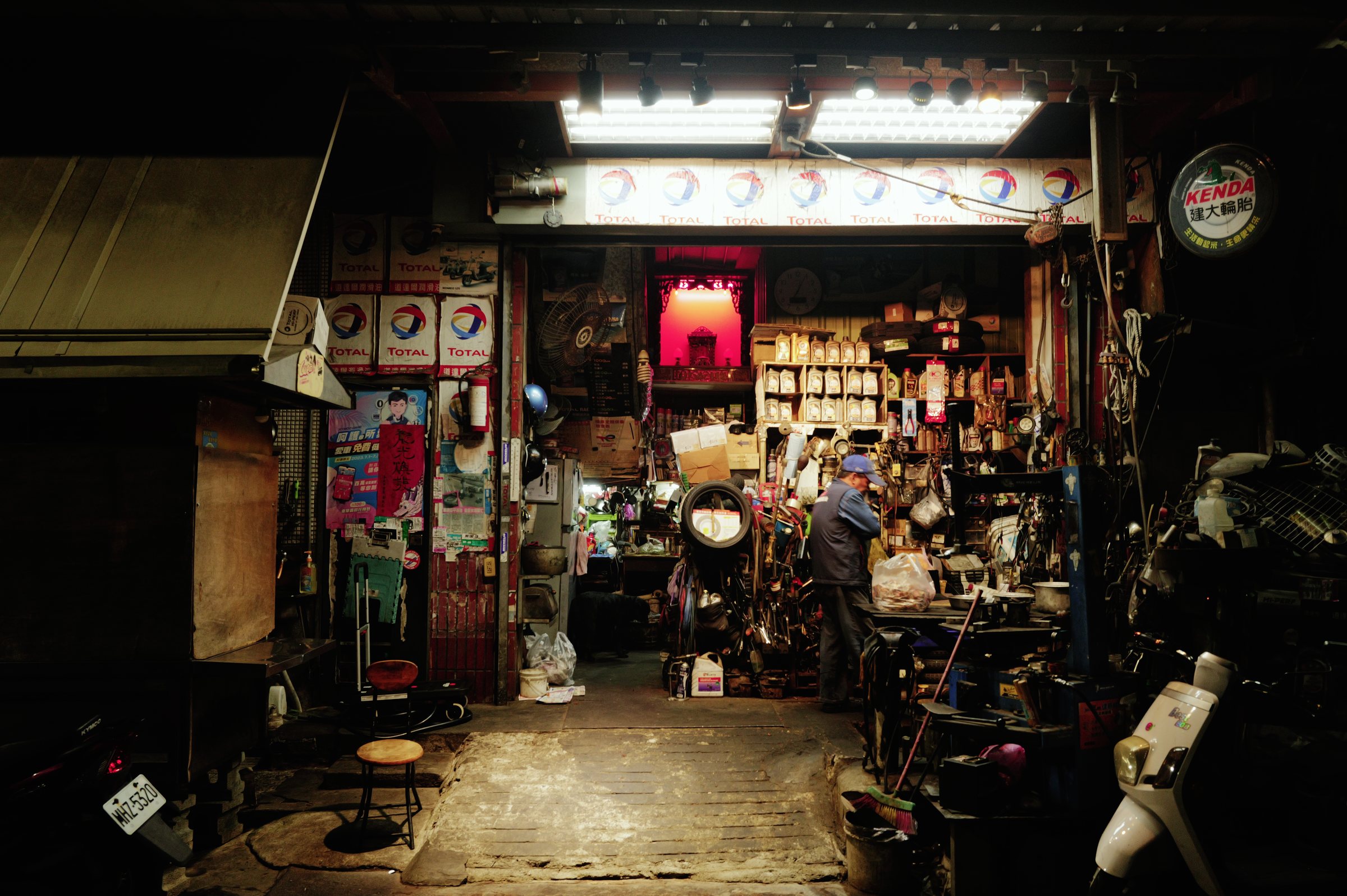 夜、通りに面した店の奥の明かりの下に座る人