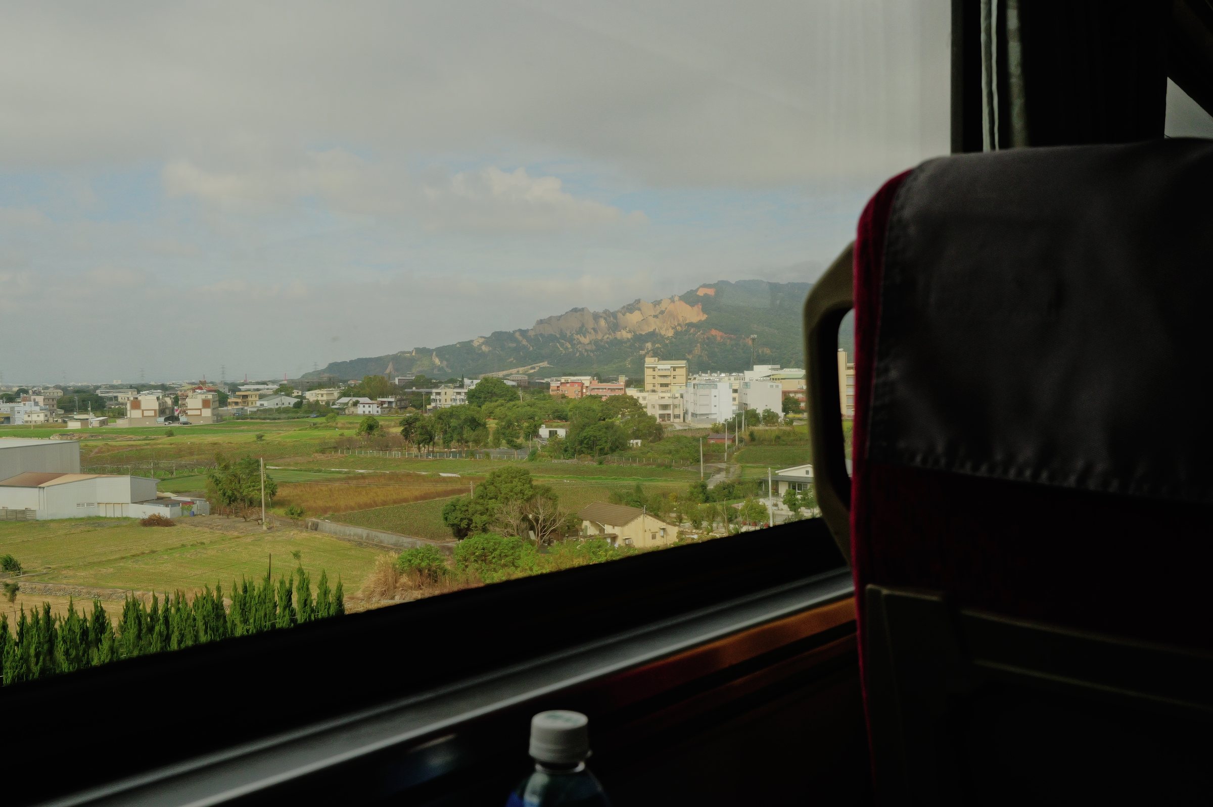 列車の窓から見る、低い山と畑と町