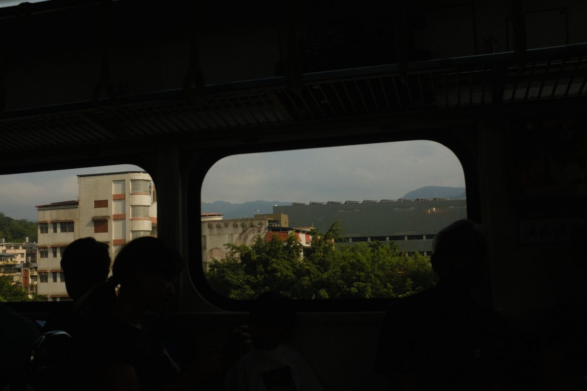 暗い車内に乗客の影が並び、四角い窓の向こうを街と山が流れていく