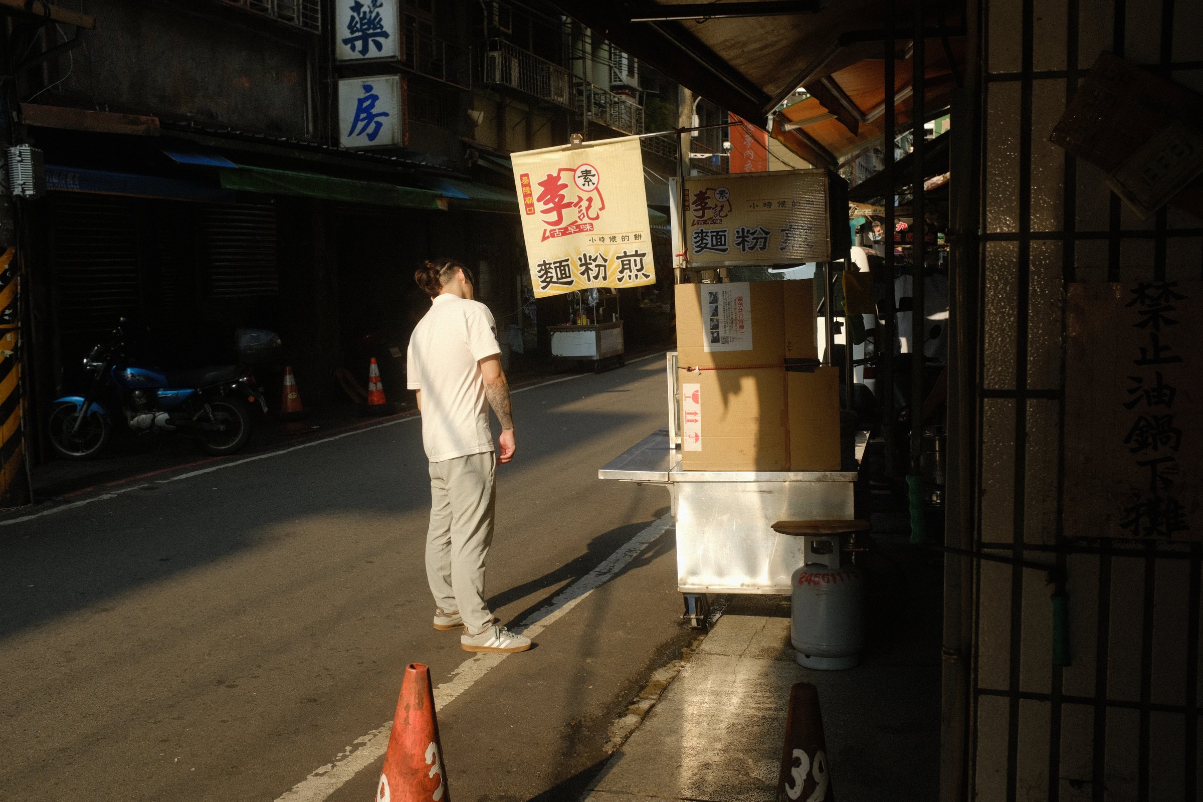 西日の差す通りに立ち、長い影を落とす男