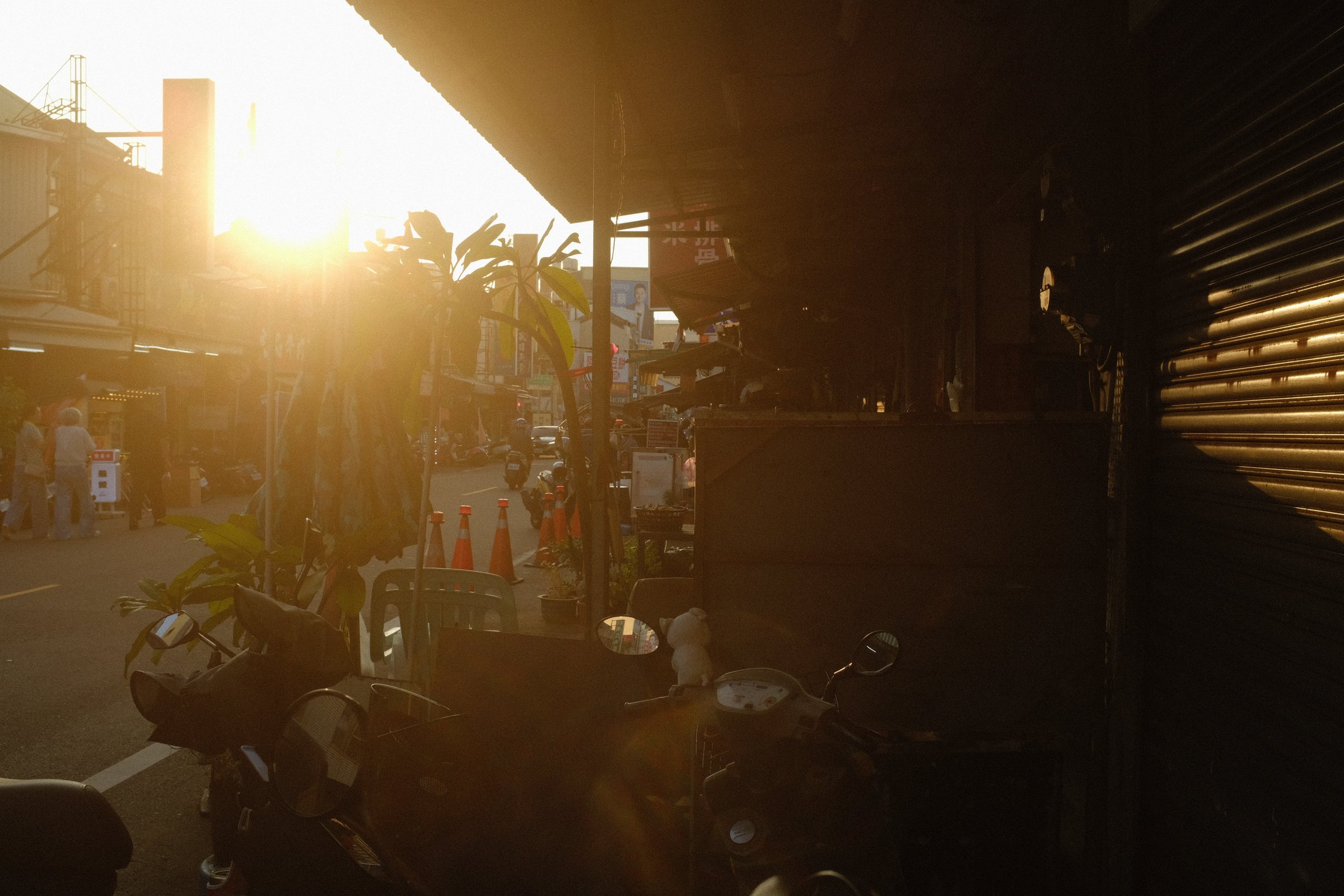 家並みのあいだに沈む夕陽と、逆光の路地