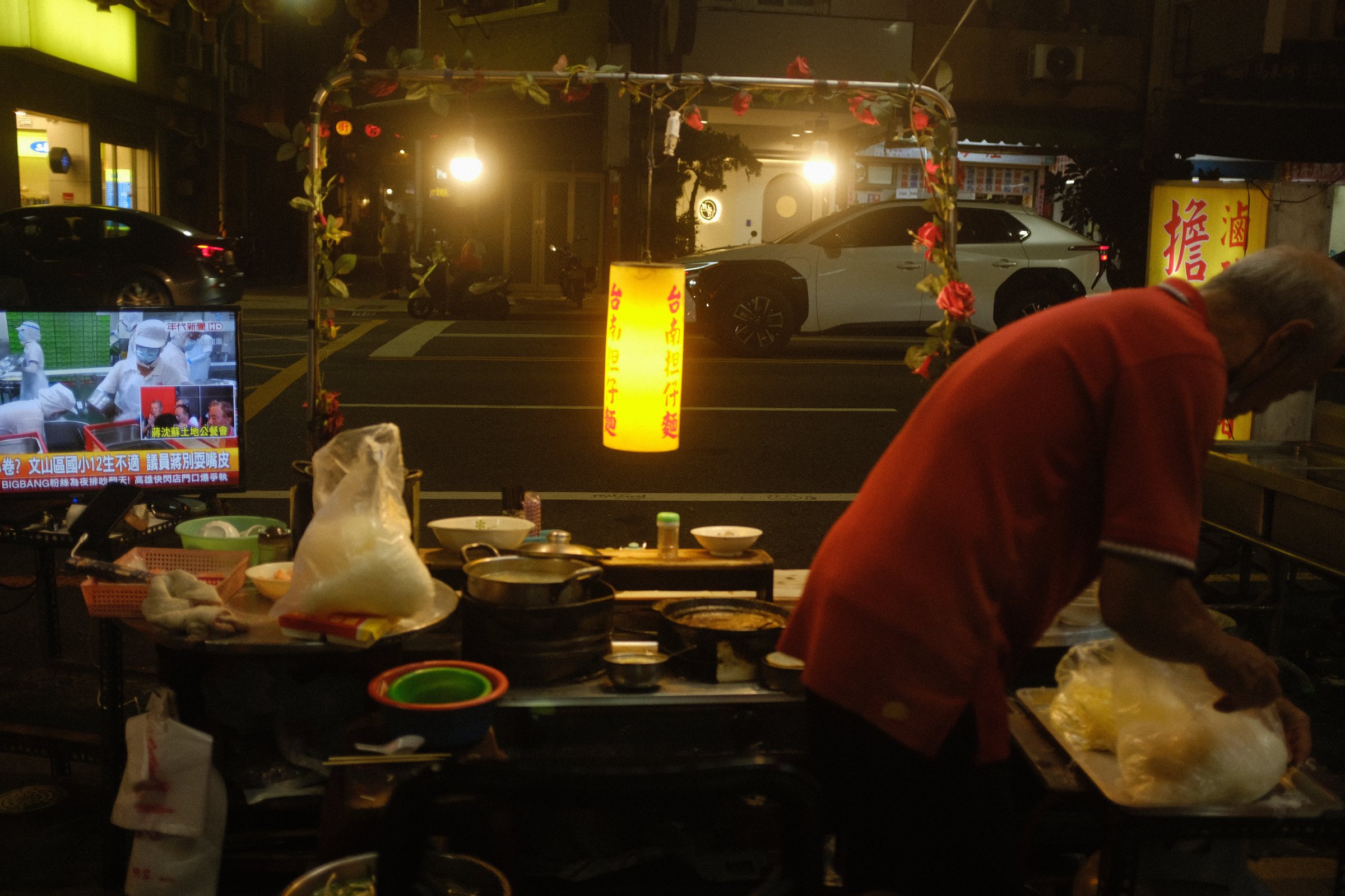 夜の屋台の灯りの下で手を動かす年配の店主