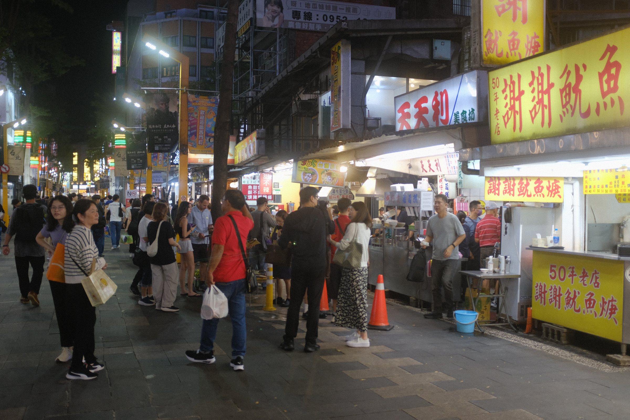 光る看板の下を人が行き交う夜市の通り