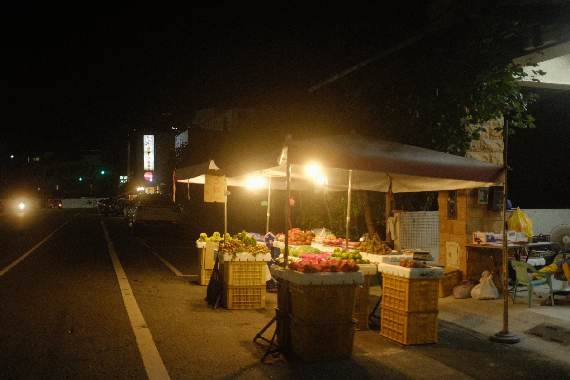 夜の道端で灯りをともす果物の屋台