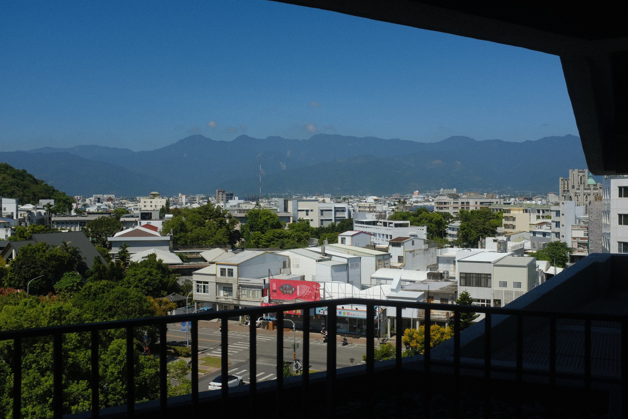 手すり越しに見る台東の家並みと、その向こうの山