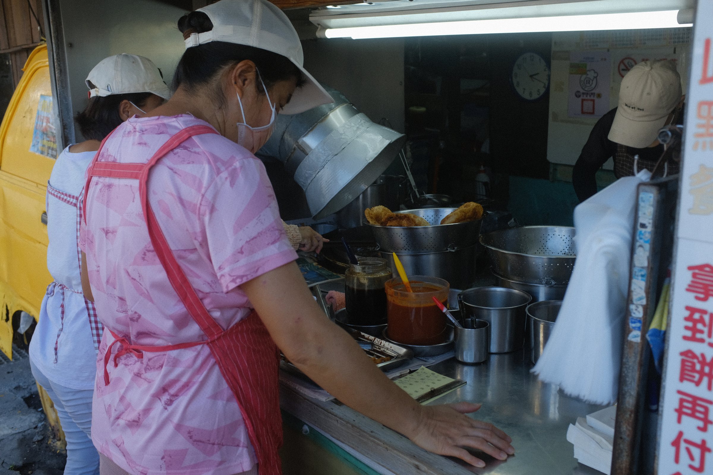 店の奥で、エプロンをつけて鍋の前に立つ人