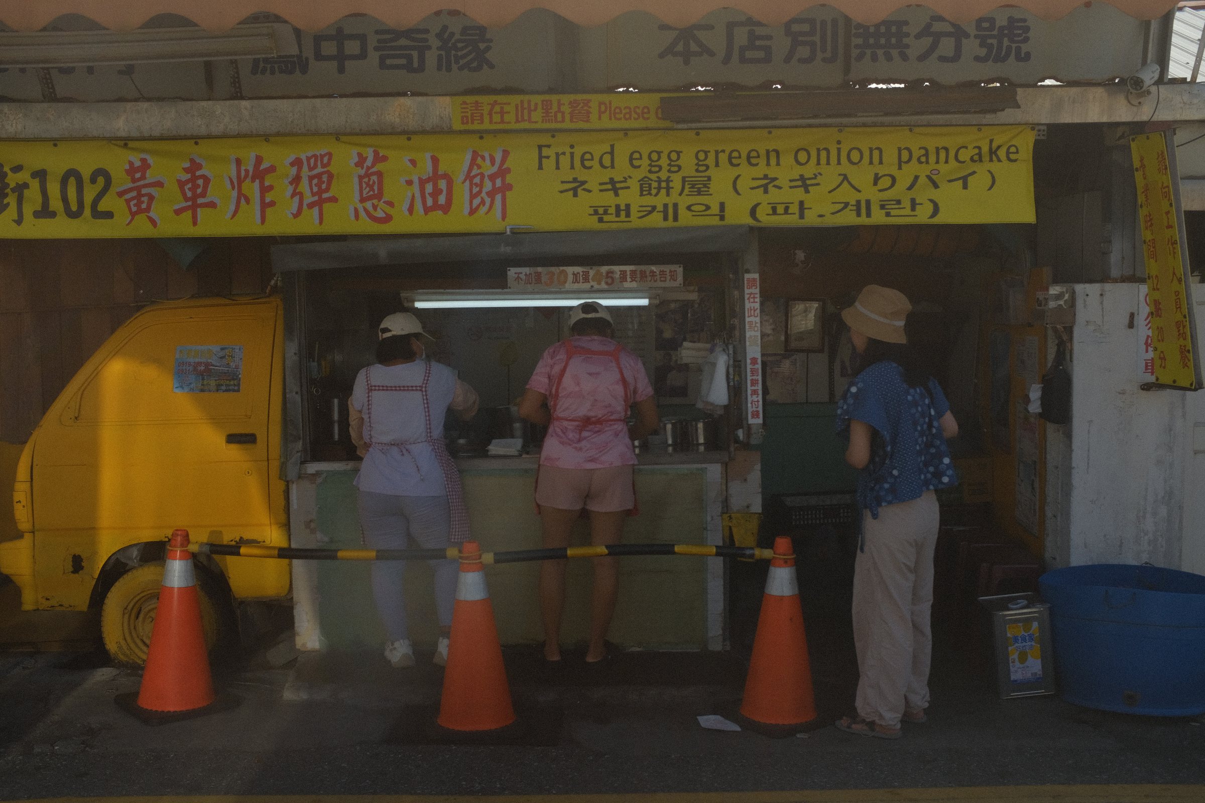 黄色い看板の蔥油餅の店と、店先に並ぶ人たち
