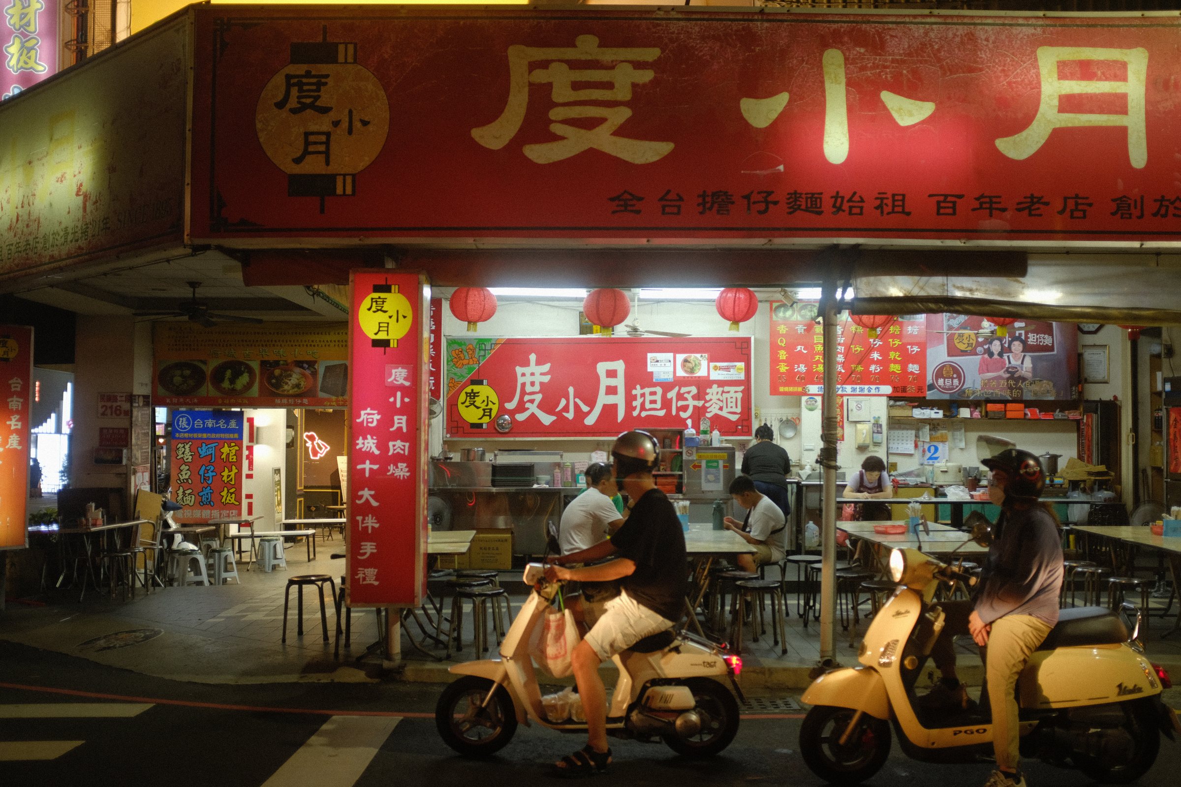 夜の度小月の店先と、前を通るバイク